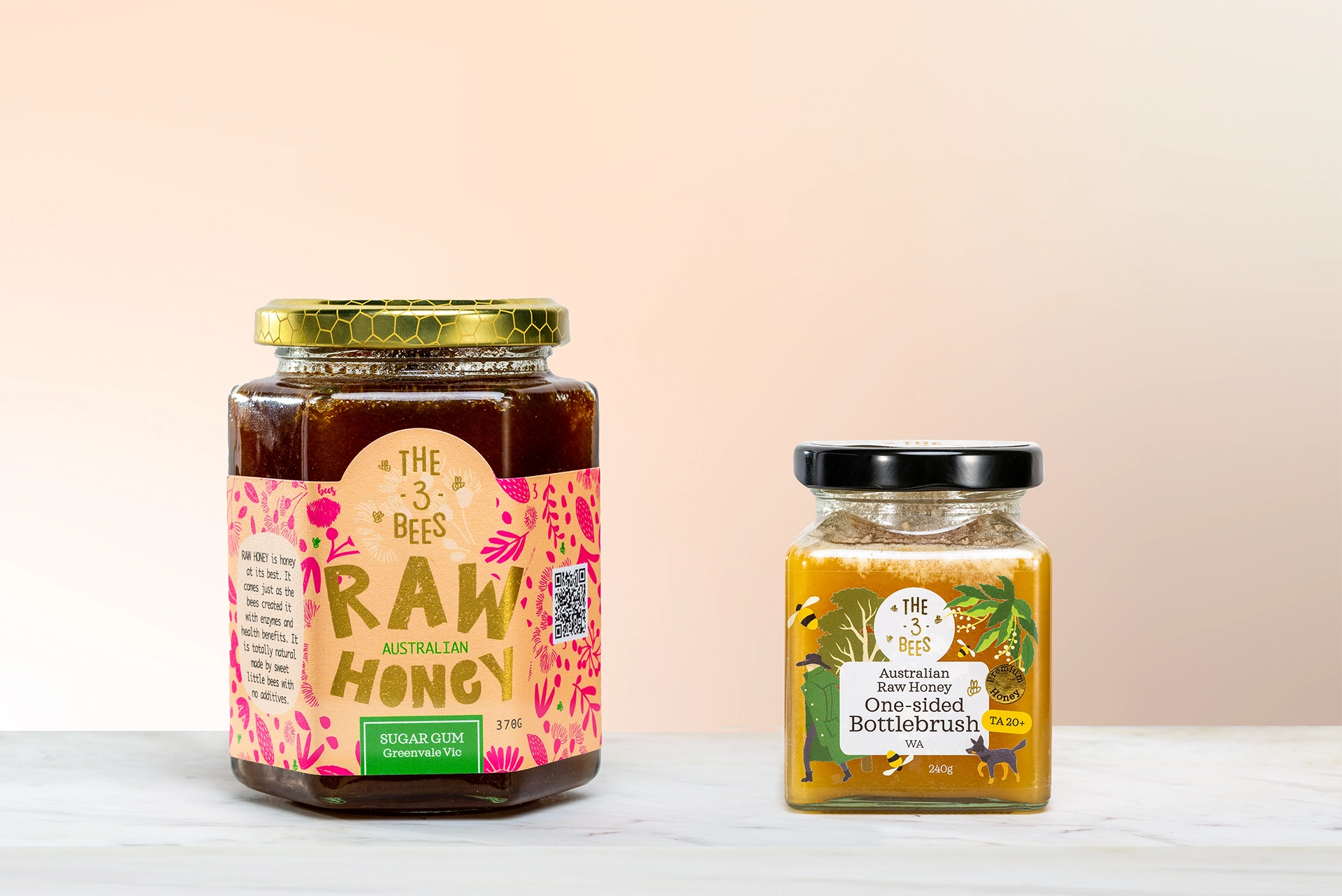 Two jars of honey, one larger and hexagonal shapped, one smaller and square shaped, both showing the name The 3 Bees